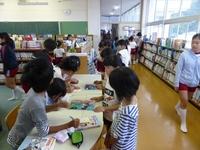 小学校の図書館で本を貸し出しをする小学生達の写真