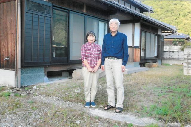 自宅の庭先に立っている笑顔のNさん夫婦の写真