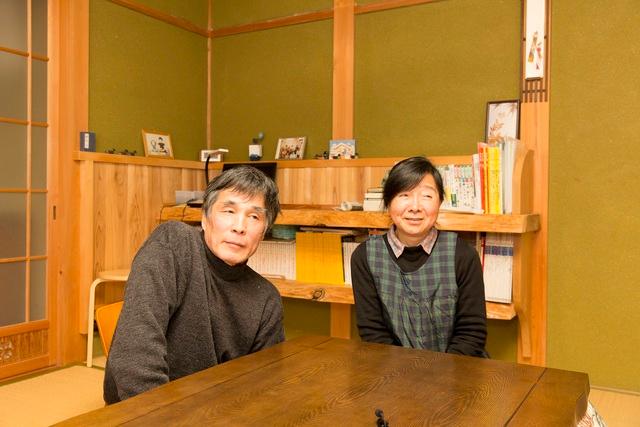 和室で本棚を背にして座り微笑む坂口さん夫婦の写真