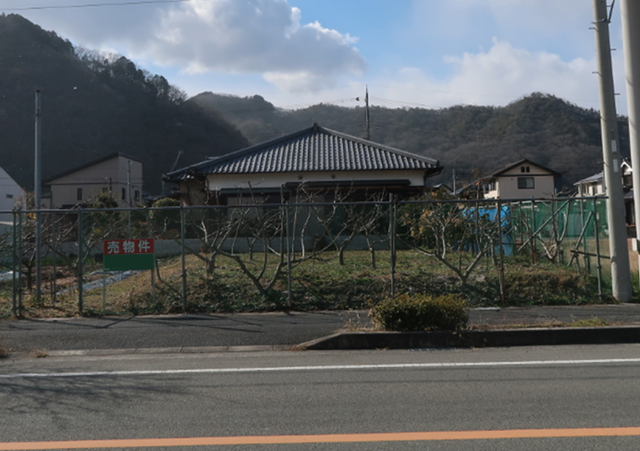 緑のフェンスで囲まれた売物件の土地