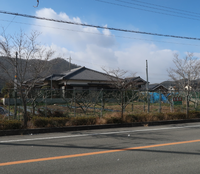 緑のフェンスで囲まれた売物件の土地を少し角度をつけて正面から写した写真