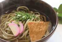 緑色の麺にネギと蒲鉾とお揚げが乗っている円心モロどんの写真