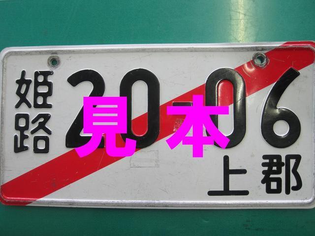 赤い斜線の入った仮ナンバープレートに姫路20-06上郡と書かれている仮ナンバープレートの見本の画像